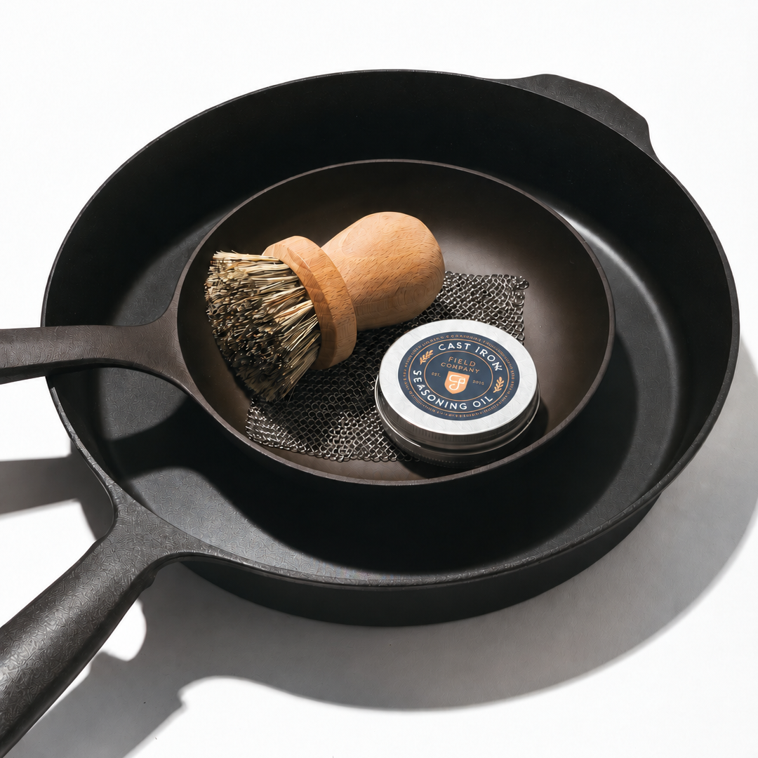 No.5 Skillet shown nestled inside No.10 skillet with our metal scrubber, wooden brush, and seasoning oil.