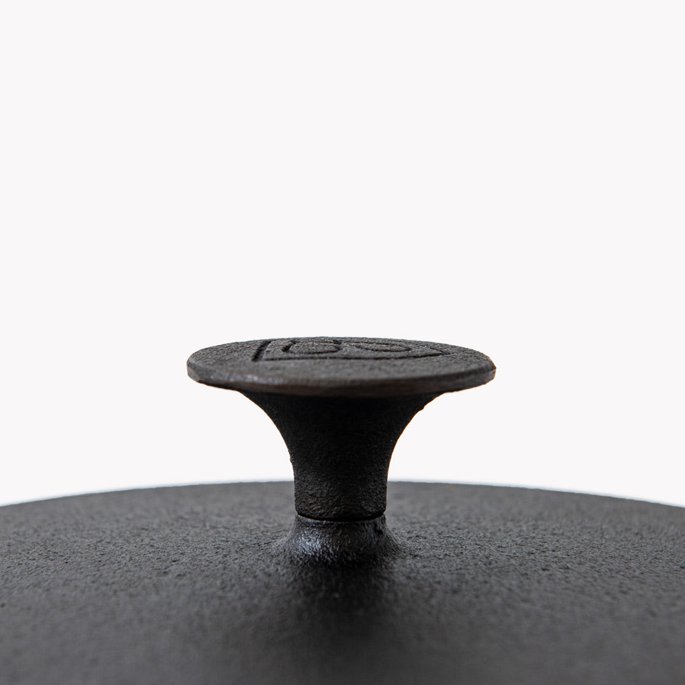 Close-up of the knob on a Field Dutch oven lid, shield medallion on top