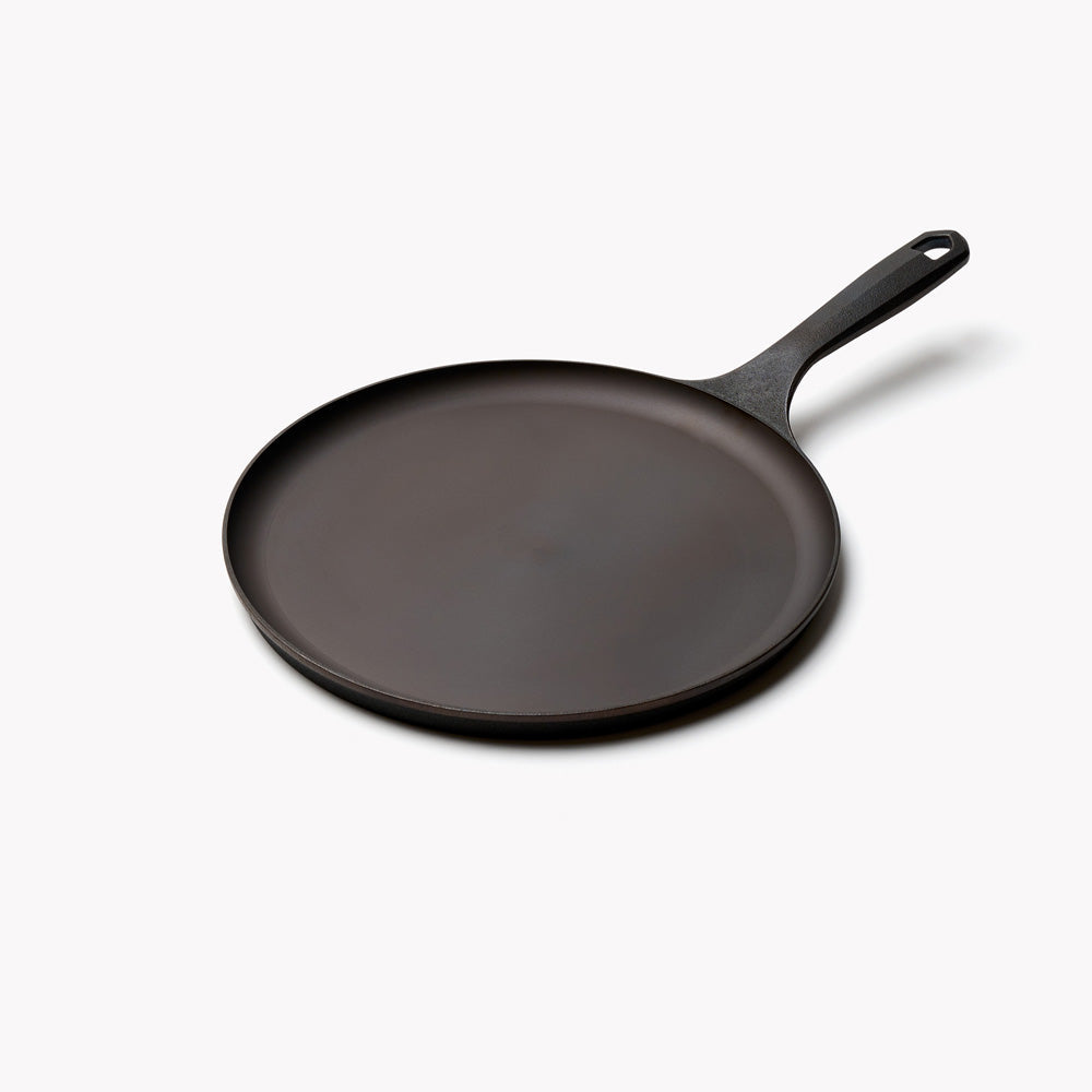 Field round cast iron griddle at an angle, flat surface with a long handle