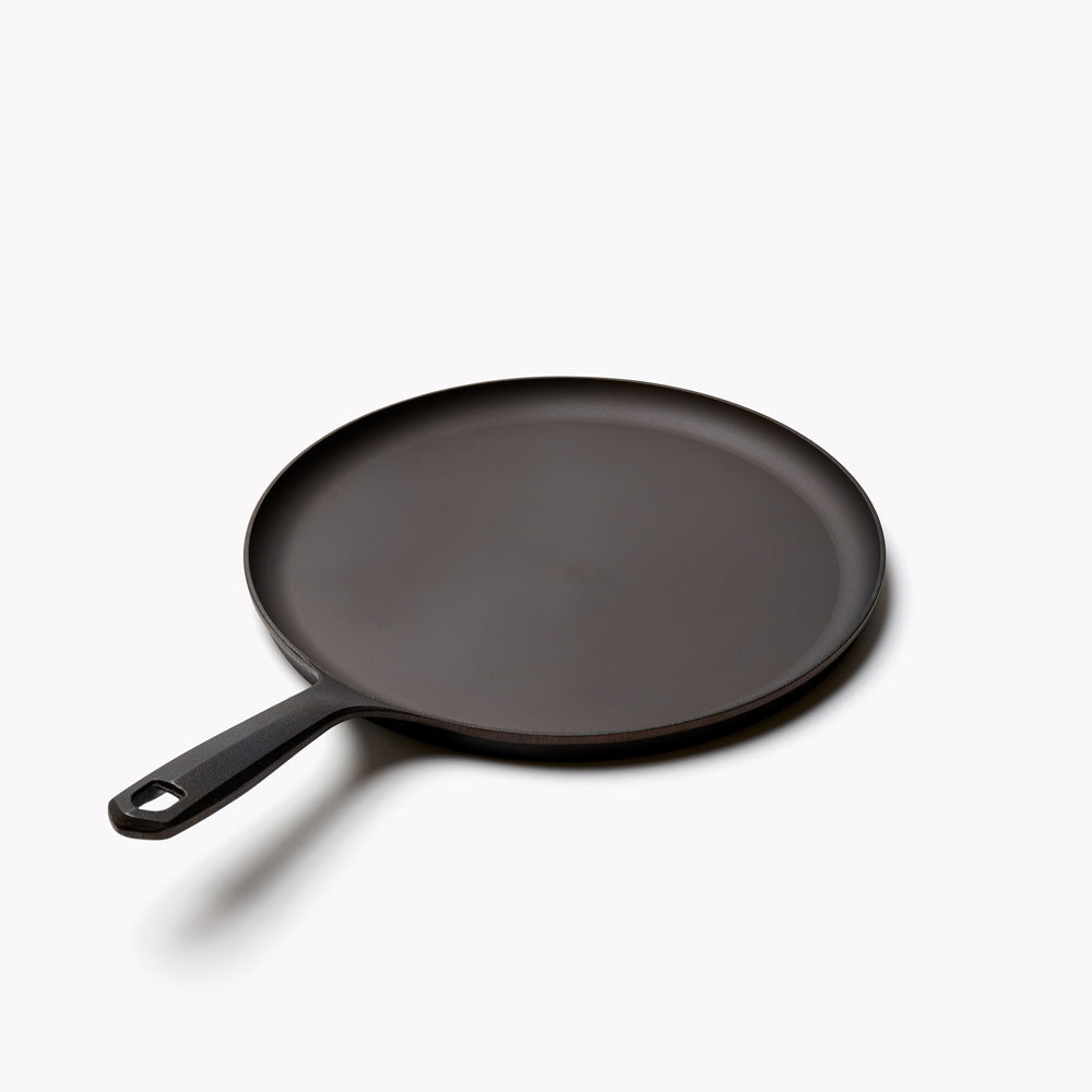 Field round cast iron griddle angled with its handle to the lower left