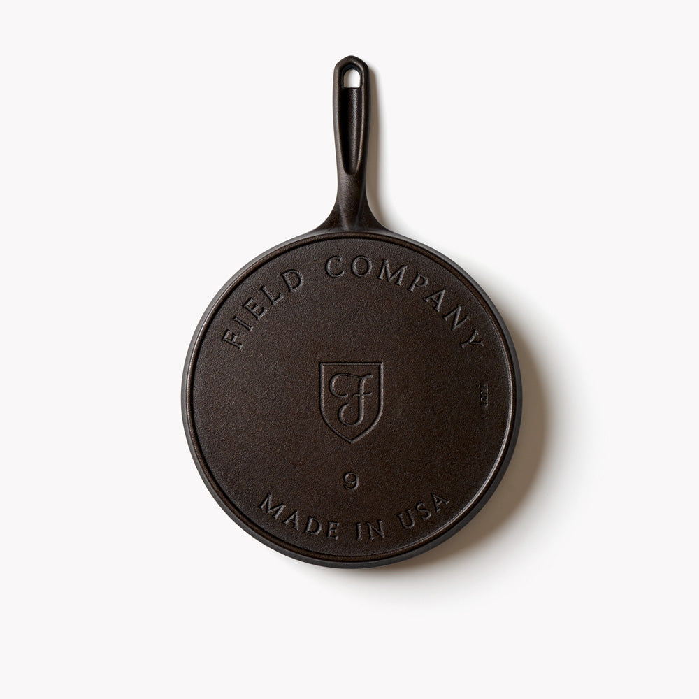 Underside of a round cast iron griddle stamped Field Company, Made in USA and the size 9