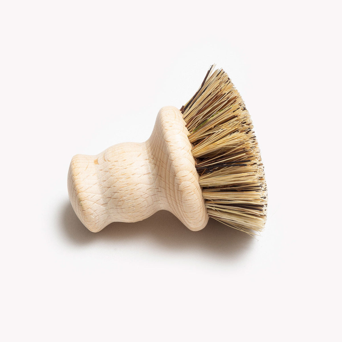 Field natural fiber brush resting on its side, showing the flared bristle head