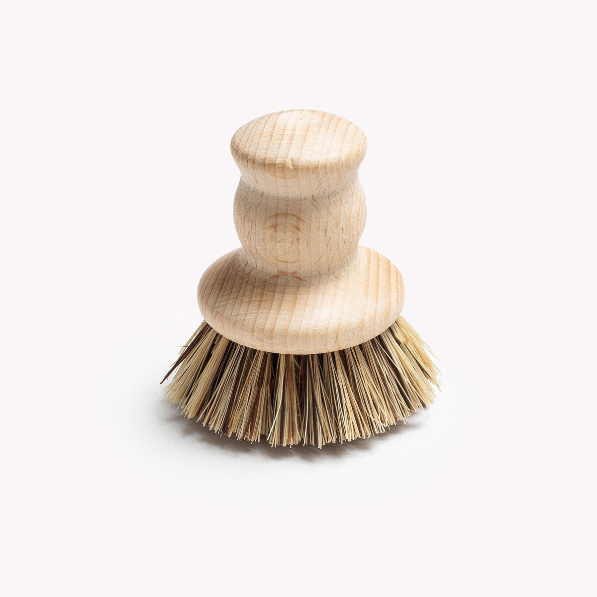 Field natural fiber brush standing upright on its bristles, turned wood handle above